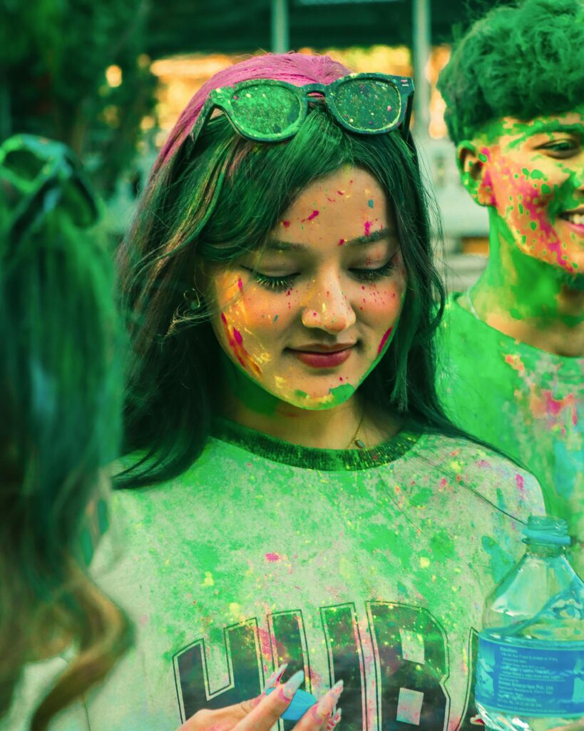 Vibrant Holi celebration with young adults covered in colorful powders, laughing and enjoying the festival.
